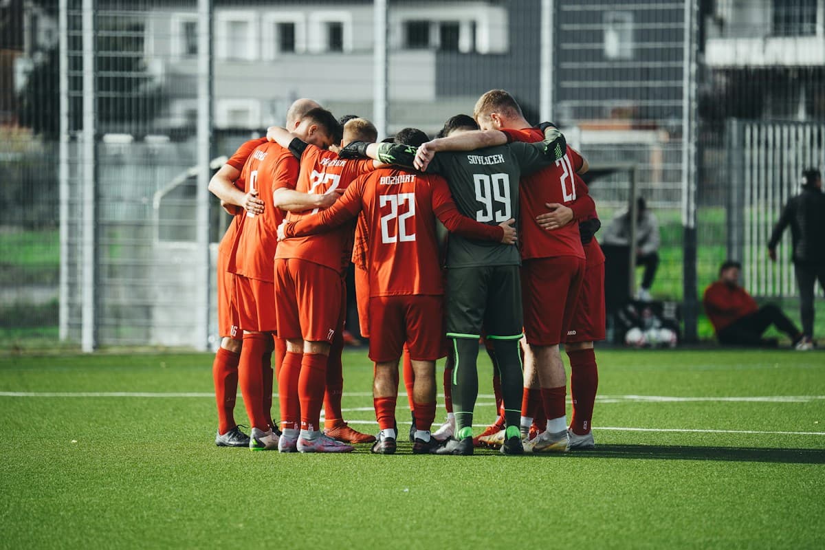 Equipo amateur de camiseta naranja abrazado en ronda antes de empezar el partido